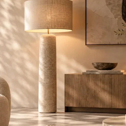 Sculpturale vloerlamp met warme stoffen kap naast een zitmeubel